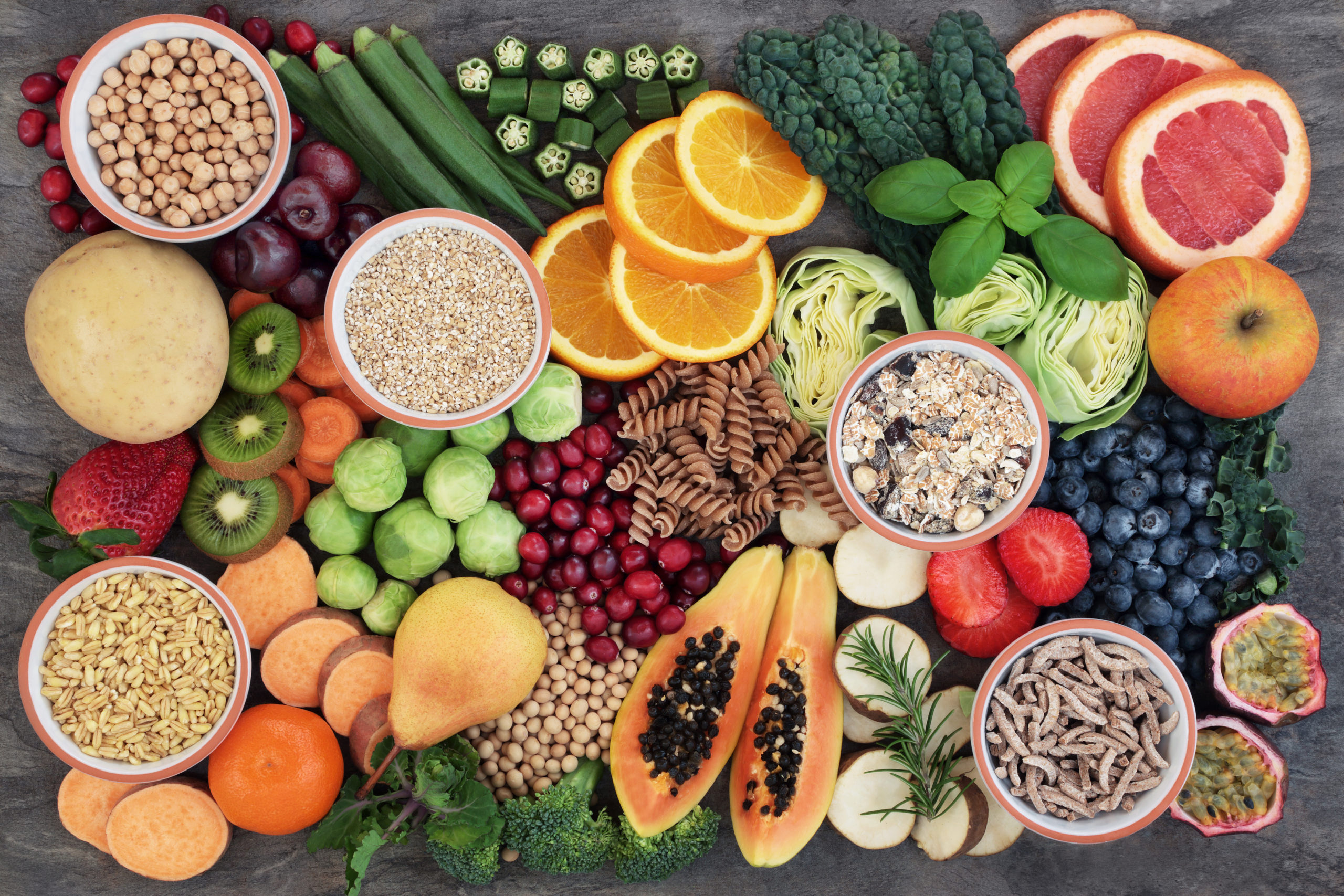 Health food concept for a high fiber diet with fruit, vegetables, cereals, whole wheat pasta, grains, legumes and herbs. Foods high in anthocyanins, antioxidants, smart carbohydrates and vitamins on marble background top view.